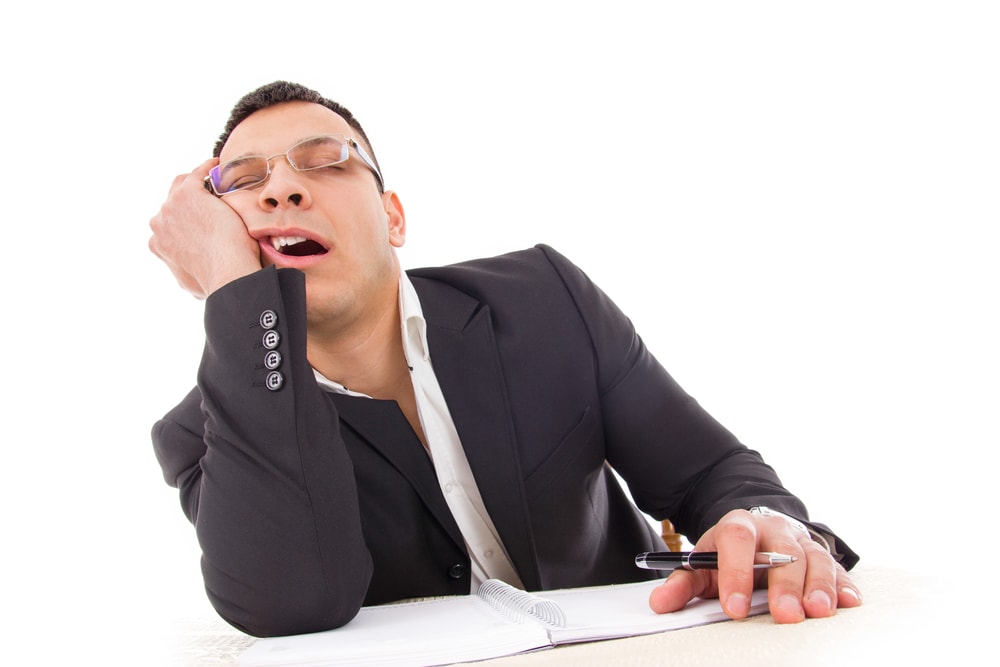 shutterstock tired businessman yawning and sleeping at work with pen in hand